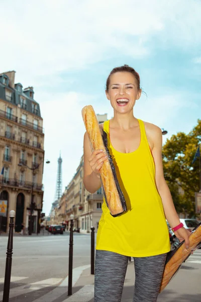 sports woman not far from Eiffel tower with 2 French baguettes