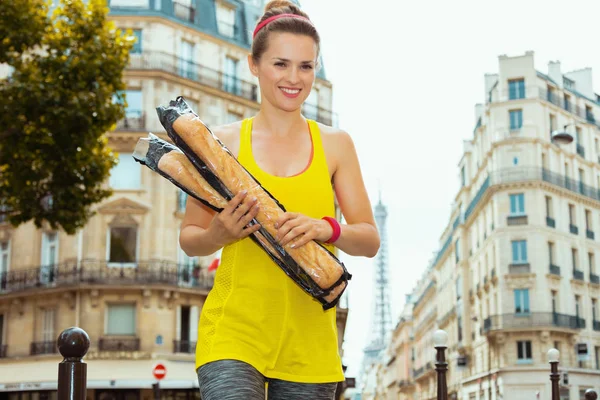 happy sports woman with 2 French baguettes crossing street