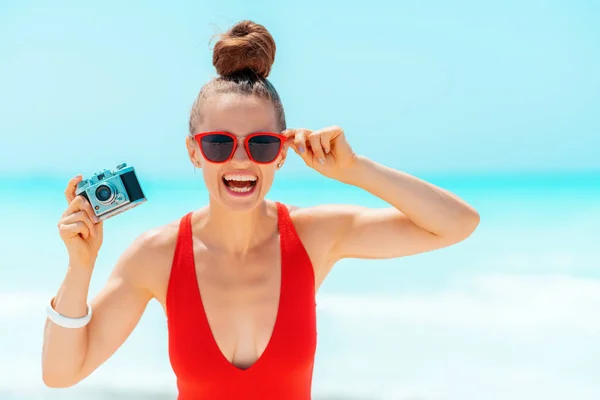 Glückliche junge Frau mit Retro-Fotokamera am Strand — Stockfoto