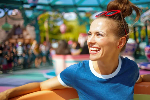 놀이기구를 가진 테마 파크에서 파란색 티셔츠를 입은 건강한 여성을 미소 짓습니다. — 스톡 사진
