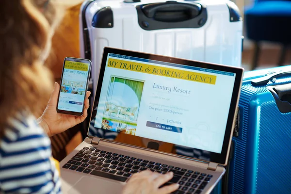 young tourist woman booking hotel on laptop and smartphone