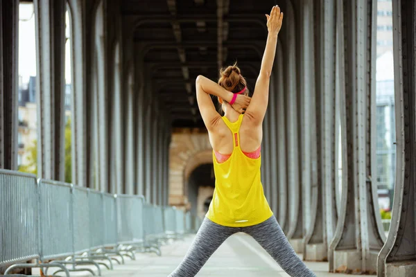 Jonge vrouw op de Pont de Bir-Hakeim-brug in Parijs stretching — Stockfoto