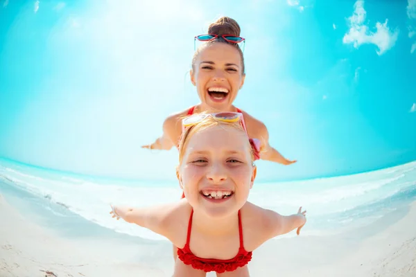 Usmívající se mladá matka a dítě na pobřeží s zábavou — Stock fotografie