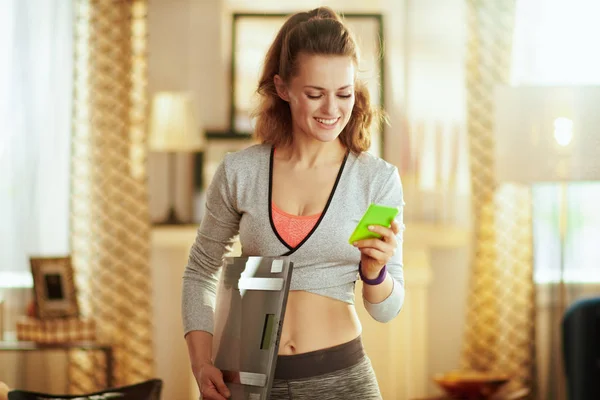 Woman with smart scale tracking weight in a fit app in phone — Stock Photo, Image