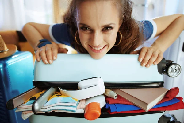Smiling stylish woman trying to close overload bag — Stock Photo, Image