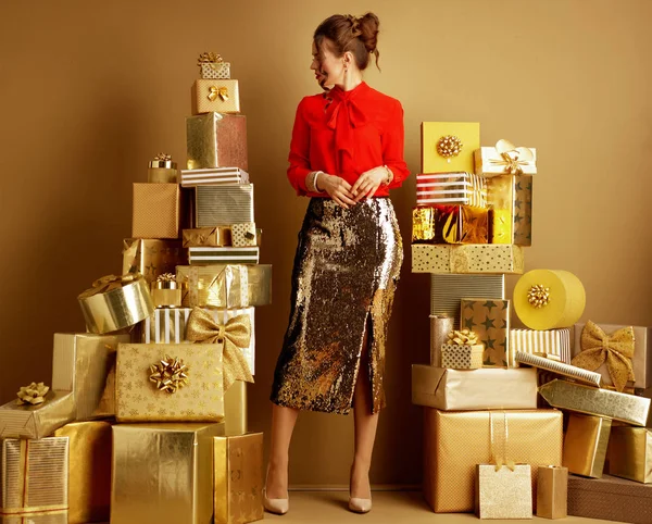 Donna guardando da parte tra 2 mucchi di regali d'oro — Foto Stock