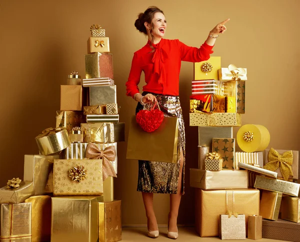 Mulher comprador com saco de compras e coração vermelho apontando para someth — Fotografia de Stock