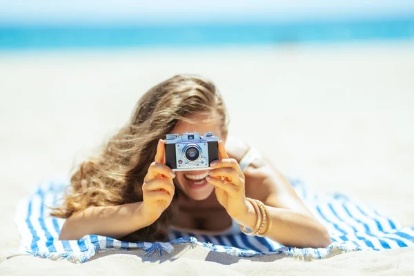 Primer plano de la cámara de fotos sosteniendo por la mujer que pone en la toalla —  Fotos de Stock