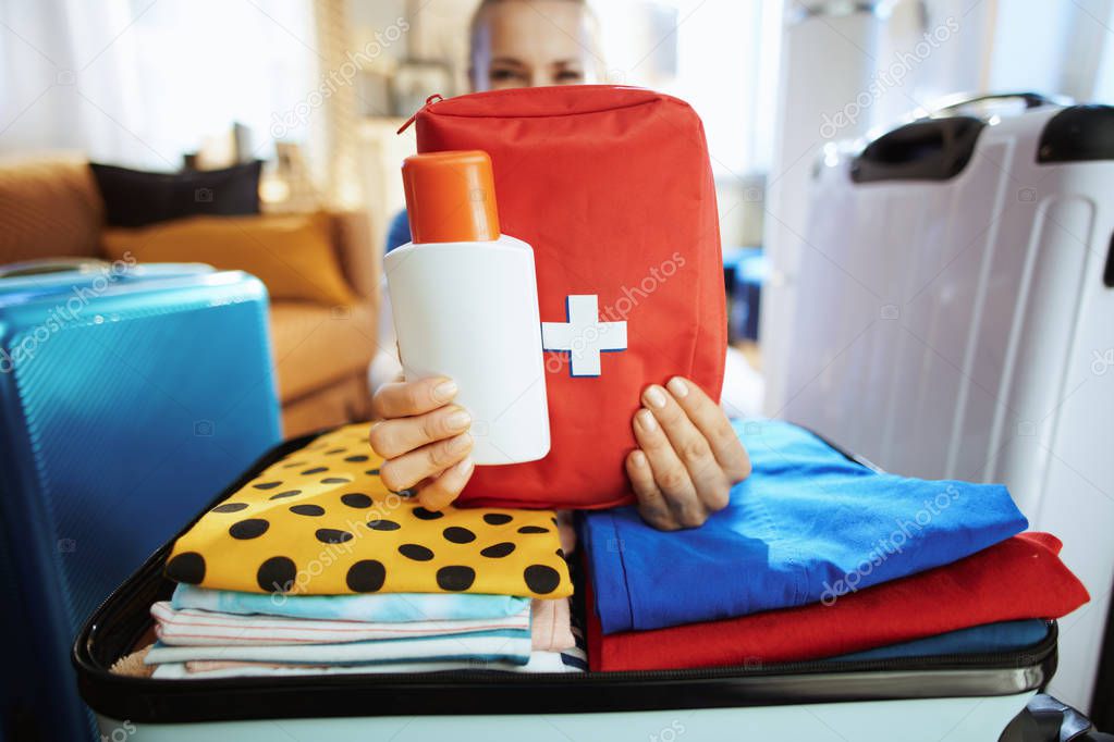 Closeup on traveller woman showing sunscreen and first aid kit