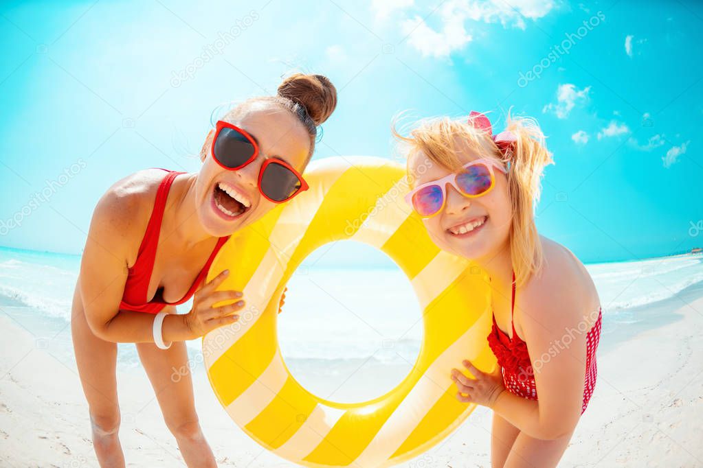 mother and child on beach holding yellow inflatable lifebuoy