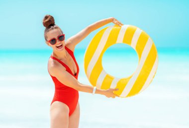 sarı şişme lifebuoy gösteren sahilde mutlu genç kadın