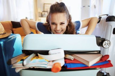 gülümseyen zarif gezgin kadın aşırı yük çanta kapatmaya çalışıyor