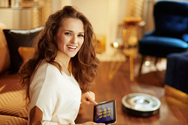 Женщина с использованием интеллектуального домашнего применения на планшетном ПК и робот вакуум — стоковое фото