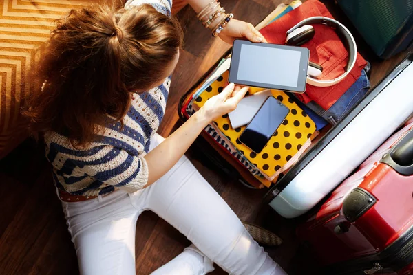 オープントラベルスーツケースに電子的なものを梱包するスタイリッシュな女性 — ストック写真