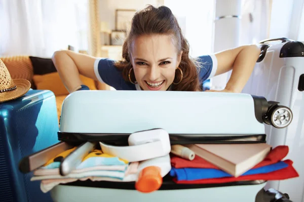 Smiling elegant traveller woman trying to close overload bag — Stock Photo, Image