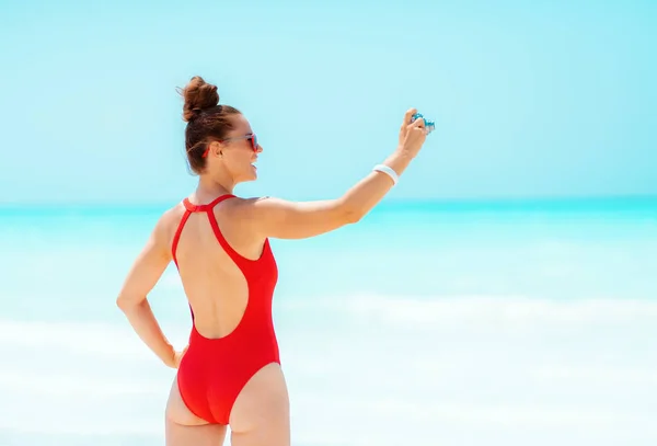 Молода жінка робить фотографії з ретро фотоапаратом на березі моря — стокове фото