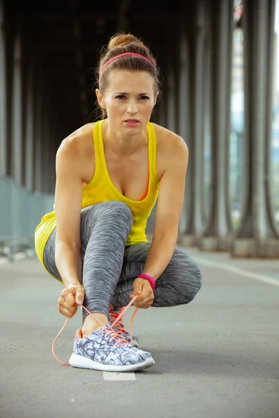 active woman looking into distance and tying shoelaces