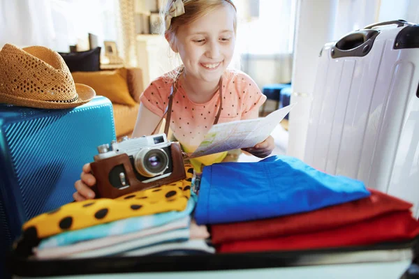 レトロなフィルムカメラとオープンスーツケースrと地図を持つ観光少女 — ストック写真