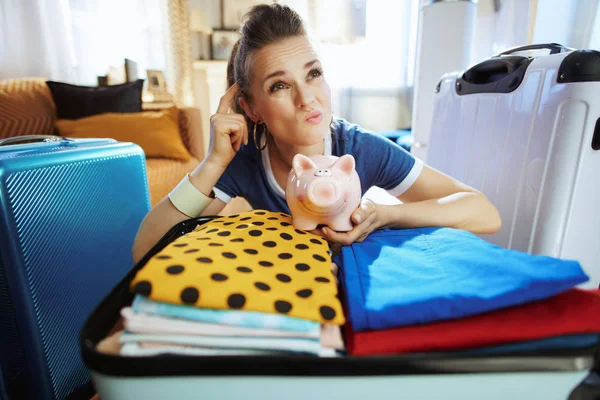 Pensive tourist woman with piggy bank calculates travel budget — Stock Photo, Image