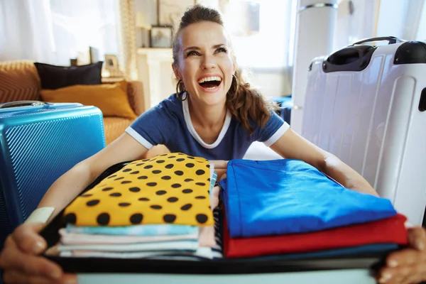 Cheerful modern tourist woman packing suitcase for holiday — Stock Photo, Image