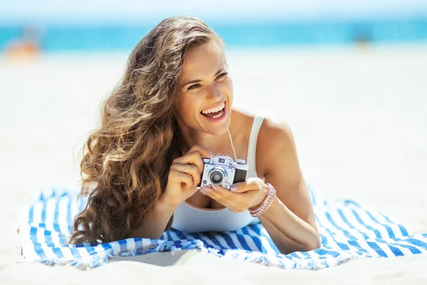 Happy woman with retro photo camera laying on striped towel — Stock Photo, Image