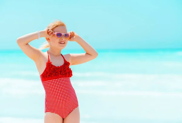 Sonriente chica moderna en la playa mirando a la distancia — Foto de Stock