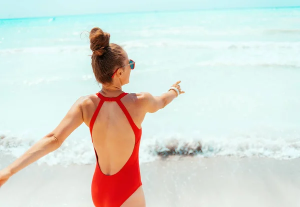 Lächelnde junge Frau in roter Bademode am Strand beim Spaß — Stockfoto