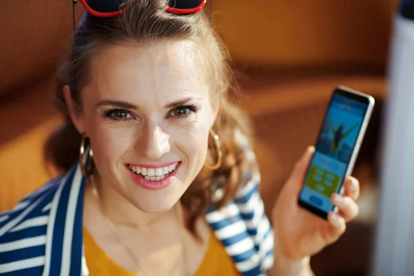 Χαμογελαστή κομψή γυναίκα αγοράζοντας αεροπορικά εισιτήρια σε απευθείας σύνδεση στο smartphone — Φωτογραφία Αρχείου