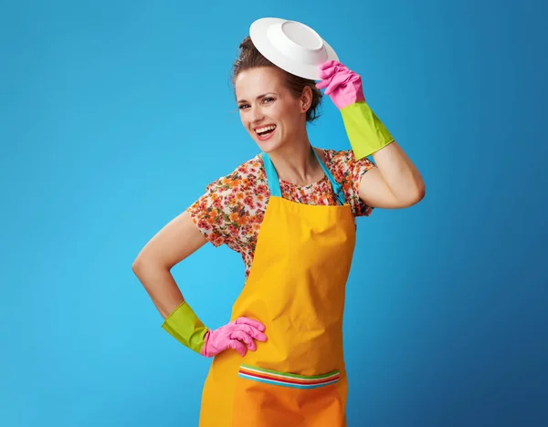 Happy young woman playing with washed plate on blue — Stock Photo, Image