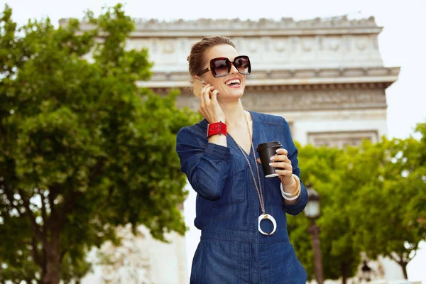 Улыбающаяся женщина-одиночка с чашкой кофе на смартфоне — стоковое фото