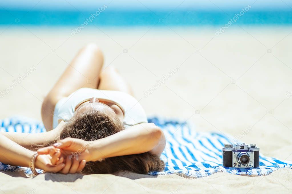 retro photo camera and woman laying on striped towel