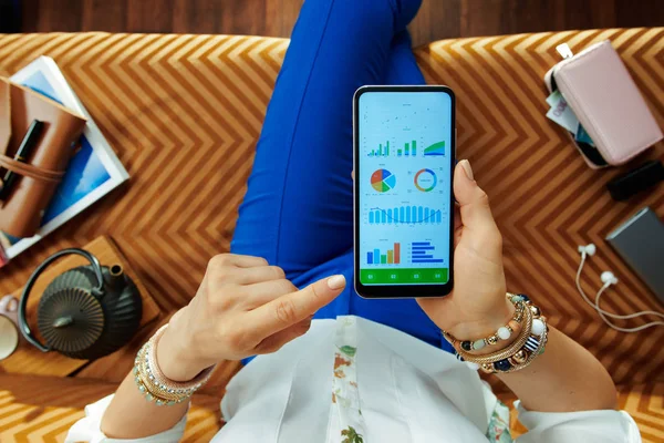 Jonge huisvrouw kijken naar grafieken op het scherm van de smartphone — Stockfoto
