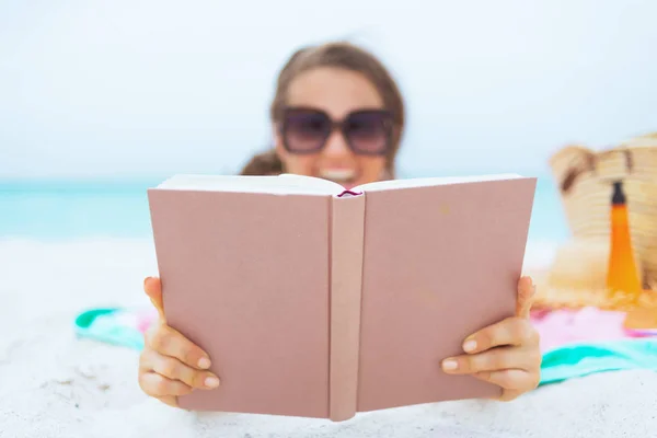 特写微笑的年轻中年妇女长卷发在优雅的黑色泳衣在白色海滩阅读书 — 图库照片