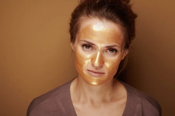 Portret Eleganckiej Kobiety Złotą Kosmetyczną Maską Twarzy Wyizolowaną Brązowym Tle — Zdjęcie stockowe