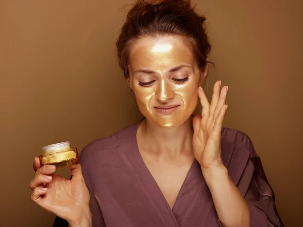 Portret Van Ontspannen Moderne Vrouw Met Gouden Cosmetische Gezichtsmasker Holding — Stockfoto