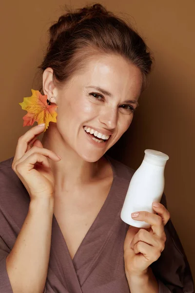 你好秋天 40岁幸福妇女穿着浴袍 秋叶耳环在青铜背景上拿着洁净牛奶的肖像 — 图库照片