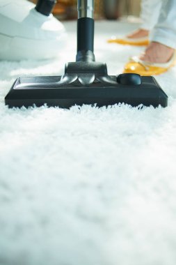 Güneşli bir günde, beyaz pofuduk halıları süpüren bir kadına yakın çekim..