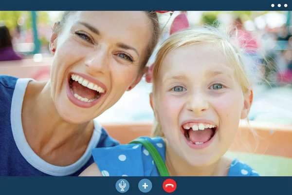 Video call screen of smiling mother and child outdoors