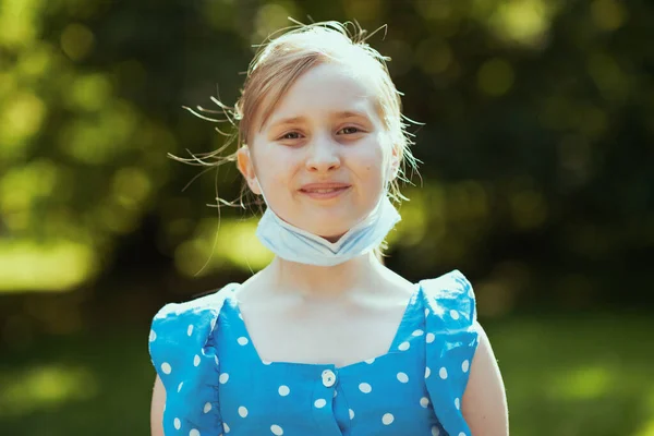 코로나 바이러스가 유행하는 동안의 공원에 의료용 마스크로 전반적으로 파란색 소녀의 — 스톡 사진