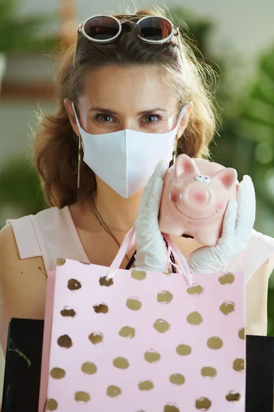 Covid 19パンデミックの間の生活 医療マスク 貯金箱 白いゴム手袋と紙のショッピングバッグとピンクのブラウスのエレガントな女性の買い物客 — ストック写真