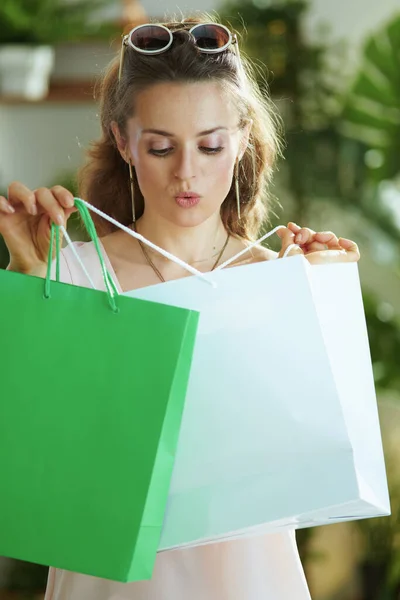 surprised young woman shopper in pink blouse with paper shopping bags.
