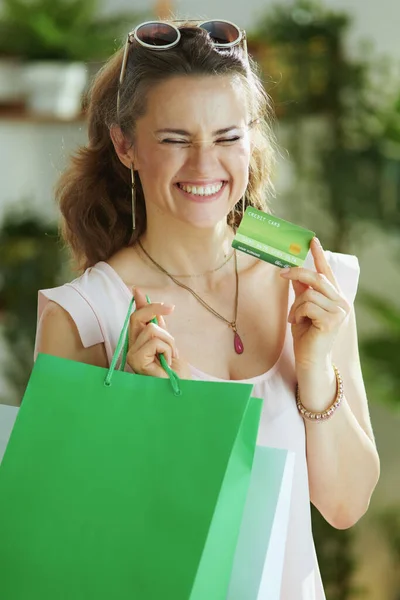 幸せなスタイリッシュな女性の買い物客でピンクのブラウスにクレジットカードと紙のショッピングバッグ — ストック写真
