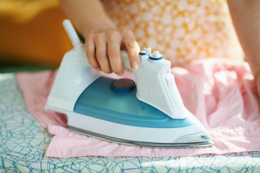 Güneşli bir günde evde, ütü masasında bir kadına yakın çekim..