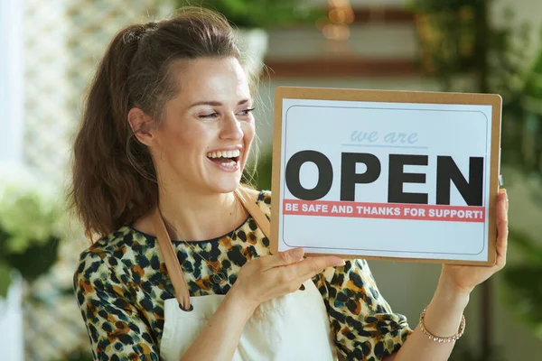 Opening small business after covid-19 pandemic. smiling stylish small business owner woman in apron showing open sign.