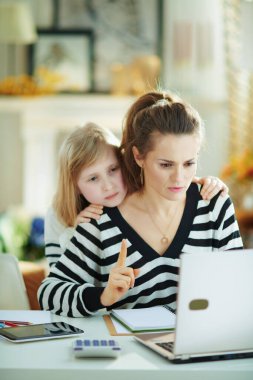 Annesi güneşli bir günde modern evde ev işleriyle meşgulken çocuk ilgi görmek istiyor..