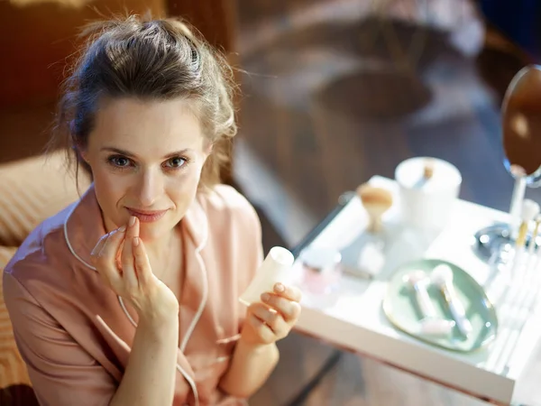 Felice Giovane Femmina Pigiama Con Tubo Cosmetico Bianco Applicando Crema — Foto Stock