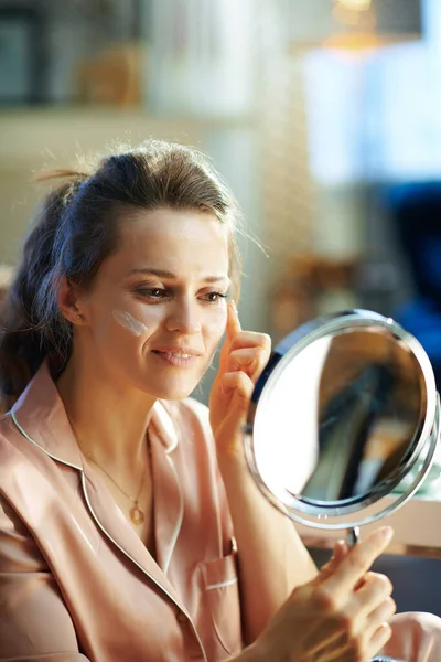 Jong Huisvrouw Pyjama Modern Huis Zonnige Winterdag Aanbrengen Gezichtscrème Kijken — Stockfoto