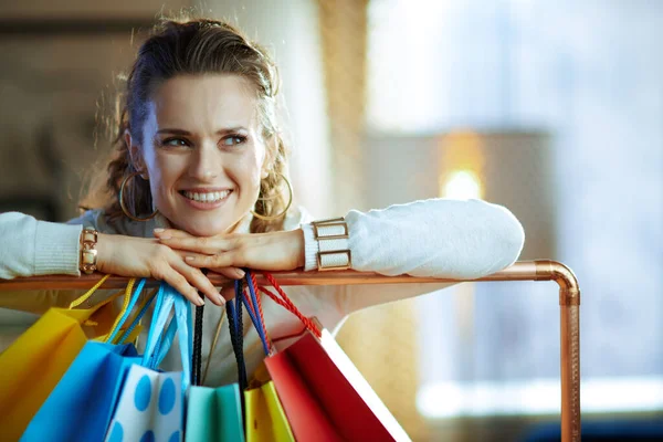 스웨터와 치마를 유행하는 여성이 복제품 공간과 옷가지에 매달려 쇼핑백 근처를 — 스톡 사진