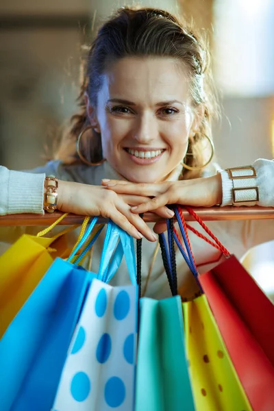 幸せな流行の肖像40歳の女性白いセーターと銅の服のレールにかかってカラフルなショッピングバッグの近くのスカート — ストック写真