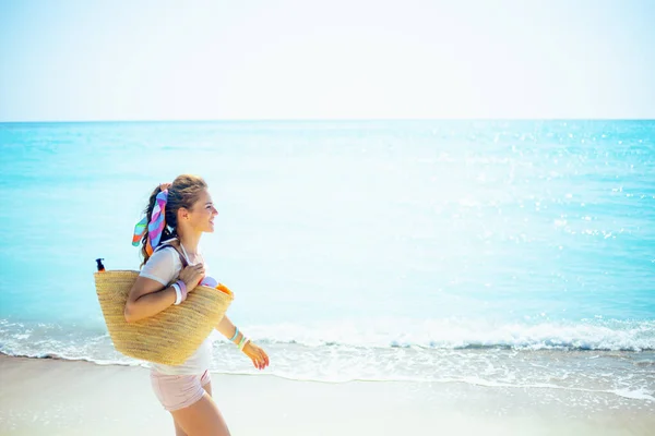 Sahilde Saman Çantalı Beyaz Tişörtlü Mutlu Genç Bir Kadın Yürüyor — Stok fotoğraf